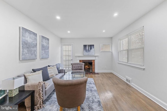 living room featuring a brick fireplace and hardwood / wood-style flooring