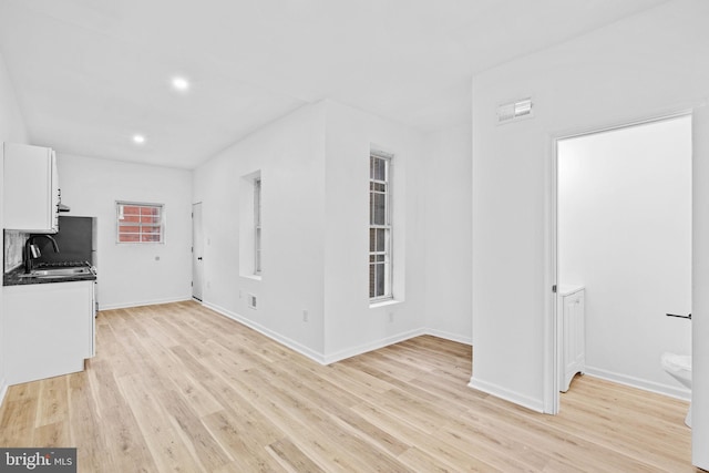 unfurnished living room featuring sink and light wood-type flooring