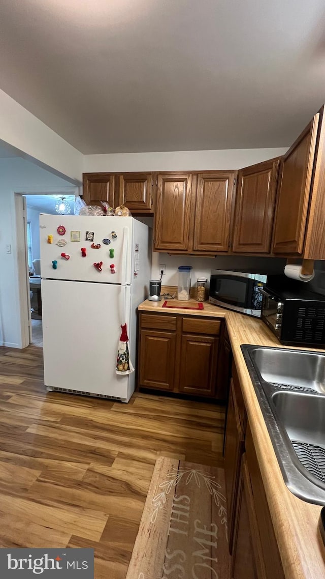 kitchen with white fridge, wood-type flooring, and sink