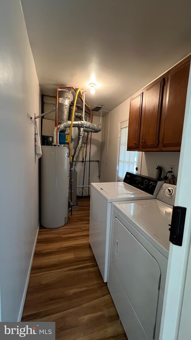 laundry area with cabinets, washing machine and dryer, dark wood-type flooring, and water heater