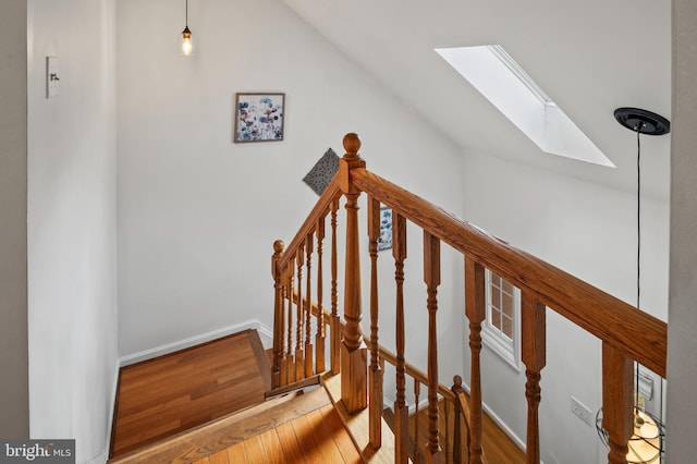 stairway with hardwood / wood-style flooring and lofted ceiling with skylight