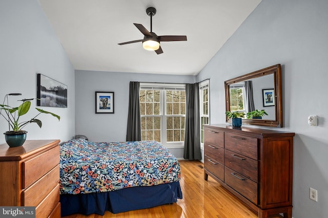 bedroom with ceiling fan, light hardwood / wood-style flooring, and vaulted ceiling