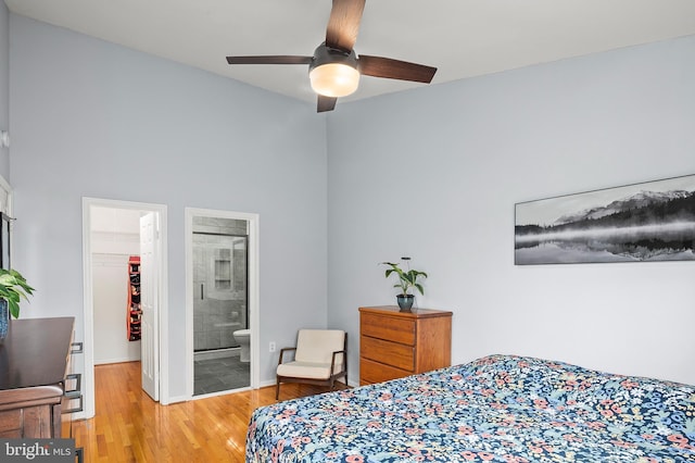 bedroom featuring ensuite bath, ceiling fan, a walk in closet, a closet, and light wood-type flooring