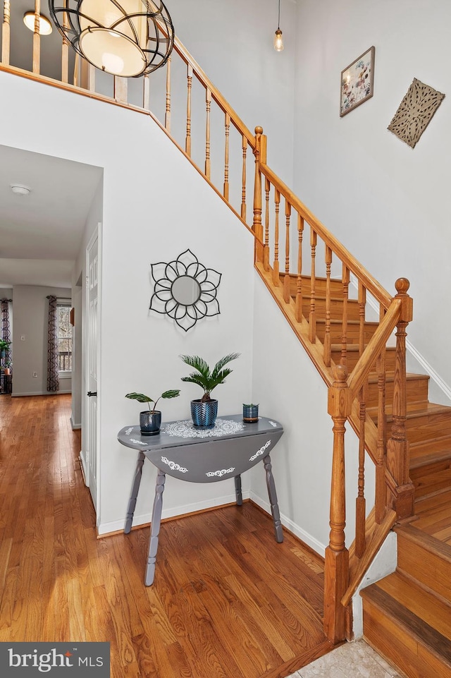 staircase with hardwood / wood-style floors and a chandelier