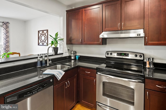 kitchen with kitchen peninsula, dark stone countertops, sink, and stainless steel appliances