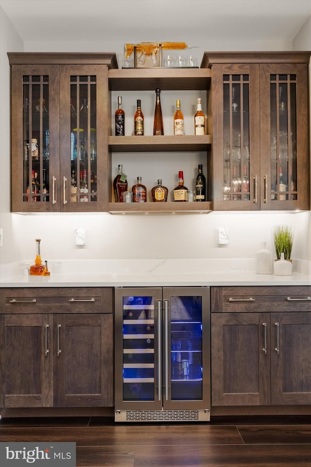 bar with dark brown cabinetry, dark wood-type flooring, and beverage cooler