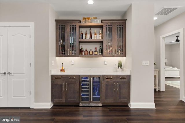 bar with dark brown cabinetry, wine cooler, ceiling fan, and dark wood-type flooring