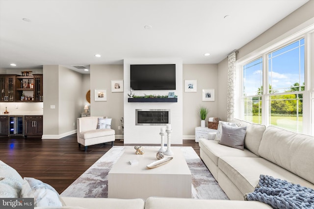 living room with a fireplace, dark wood-type flooring, beverage cooler, and bar area