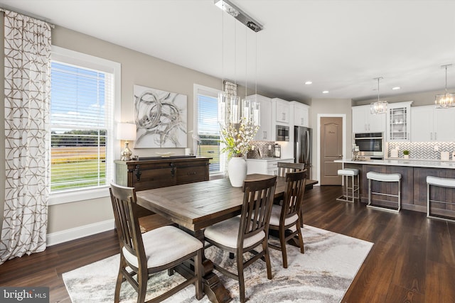 dining area with plenty of natural light, dark wood-type flooring, and an inviting chandelier