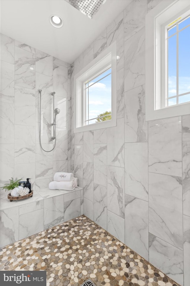 bathroom with a tile shower and a wealth of natural light