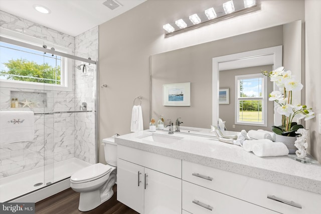 bathroom with hardwood / wood-style flooring, vanity, toilet, and a shower with door