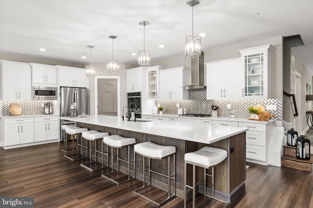 kitchen featuring appliances with stainless steel finishes, dark hardwood / wood-style flooring, a spacious island, and wall chimney range hood