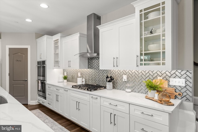 kitchen featuring light stone countertops, stainless steel appliances, white cabinets, and wall chimney exhaust hood