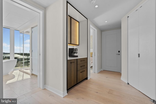 corridor with light hardwood / wood-style floors and expansive windows