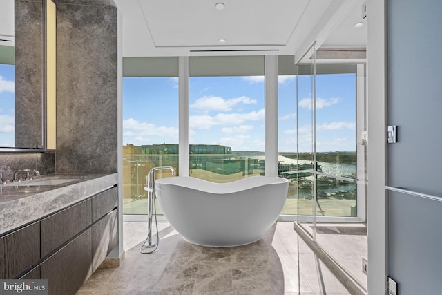 bathroom with a washtub, a water view, floor to ceiling windows, and a healthy amount of sunlight