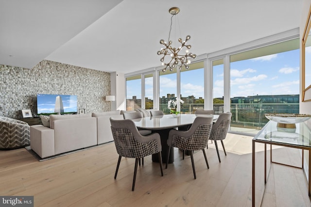 dining area featuring expansive windows, light hardwood / wood-style floors, and an inviting chandelier