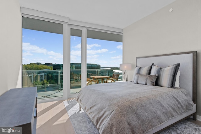 bedroom featuring access to outside, expansive windows, and wood-type flooring