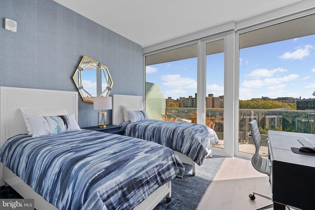 bedroom featuring wood-type flooring, access to outside, and multiple windows