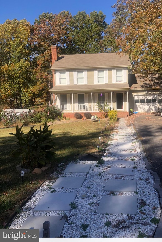 view of front of property featuring covered porch, a garage, and a front yard