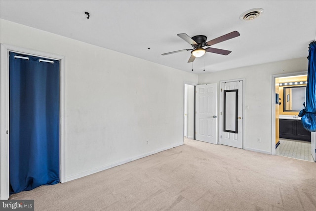 unfurnished bedroom with light colored carpet, ensuite bath, and ceiling fan