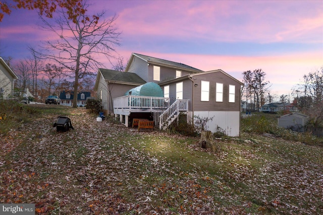 property exterior at dusk featuring a lawn and a wooden deck