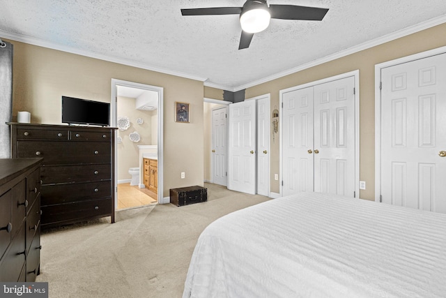 carpeted bedroom with two closets, crown molding, ceiling fan, a textured ceiling, and connected bathroom