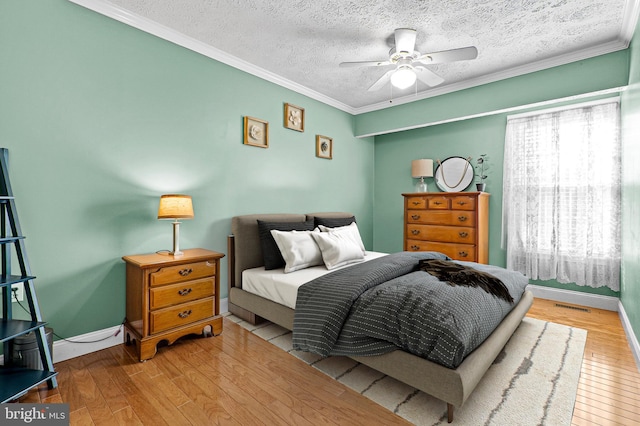 bedroom featuring ceiling fan, crown molding, a textured ceiling, and light hardwood / wood-style flooring