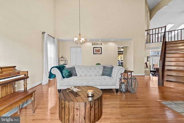 living room with light hardwood / wood-style floors, a high ceiling, and an inviting chandelier