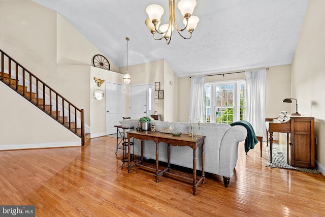 living room featuring a textured ceiling, light wood-type flooring, high vaulted ceiling, and a notable chandelier