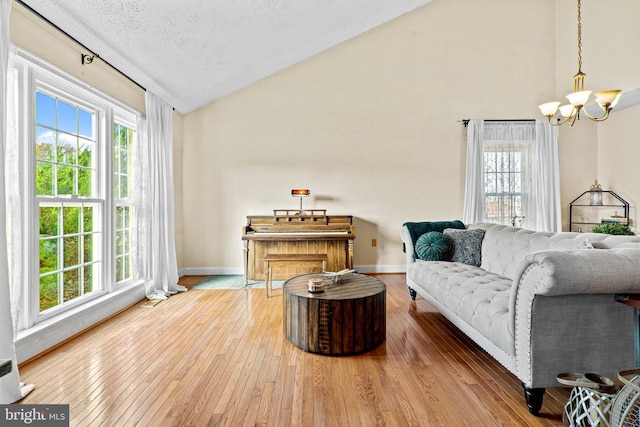 living room with a notable chandelier, lofted ceiling, wood-type flooring, and a textured ceiling