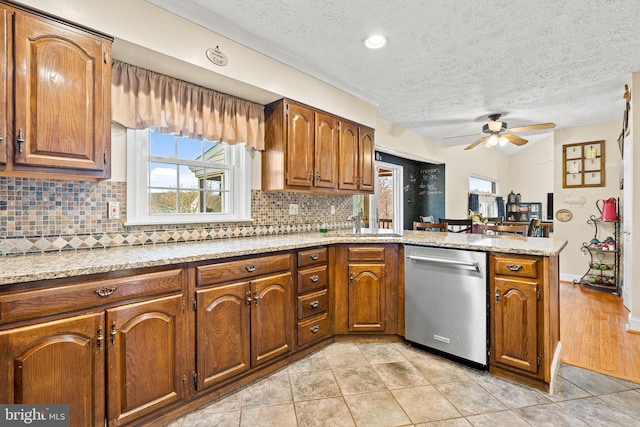 kitchen featuring stainless steel dishwasher, decorative backsplash, ceiling fan, and kitchen peninsula