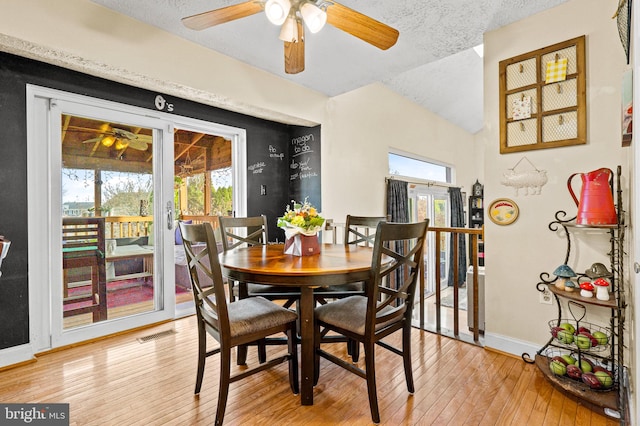 dining area featuring a textured ceiling, light wood-type flooring, french doors, and lofted ceiling