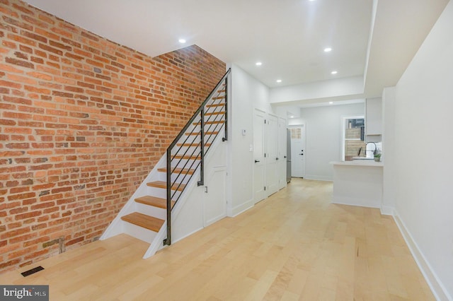 stairs with hardwood / wood-style flooring and brick wall