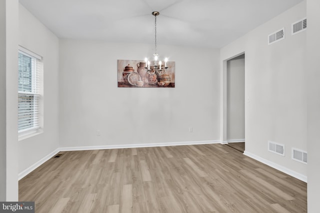 empty room with light hardwood / wood-style floors and an inviting chandelier