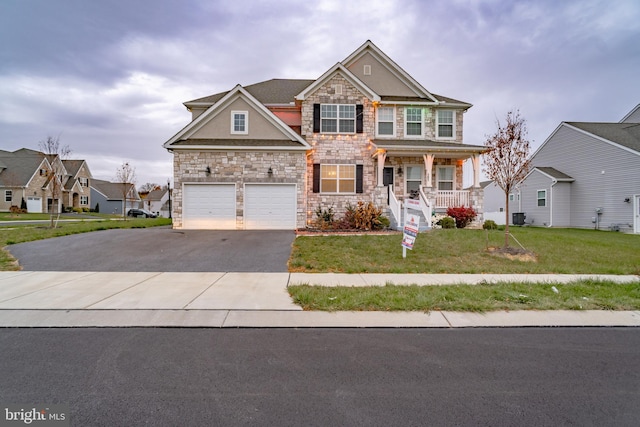 craftsman inspired home featuring a porch, a garage, and a front lawn