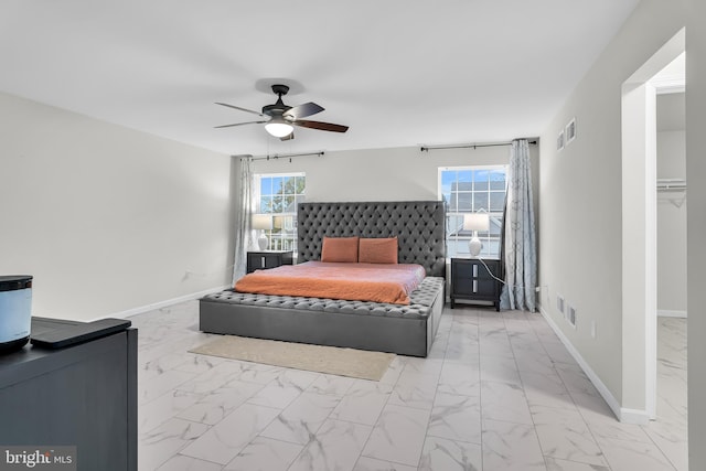 bedroom with multiple windows, a walk in closet, and ceiling fan