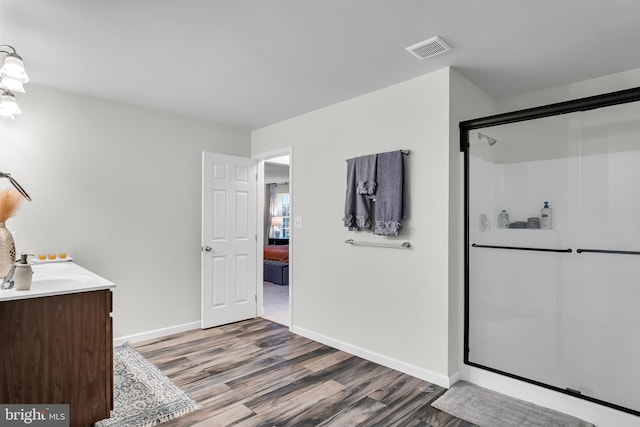 bathroom with hardwood / wood-style floors, vanity, and a shower with door