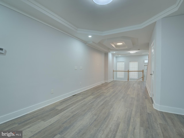 unfurnished room featuring light wood-type flooring, crown molding, and a tray ceiling