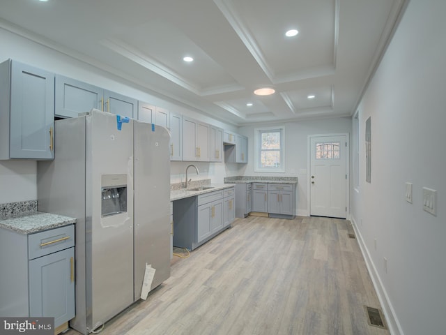 kitchen with stainless steel fridge, coffered ceiling, sink, beam ceiling, and light hardwood / wood-style floors