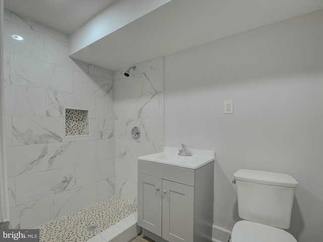 bathroom featuring a tile shower, vanity, and toilet