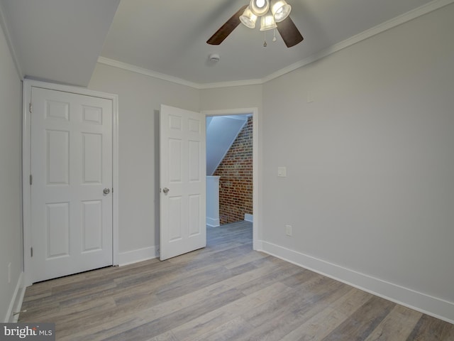 unfurnished bedroom featuring ceiling fan, ornamental molding, brick wall, and light hardwood / wood-style flooring