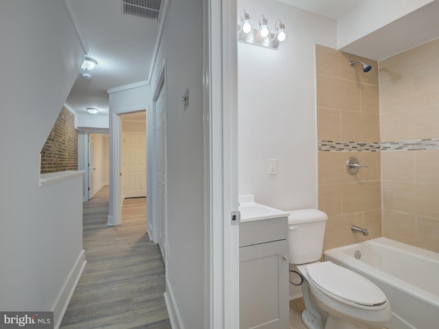 full bathroom featuring tiled shower / bath combo, crown molding, wood-type flooring, toilet, and vanity