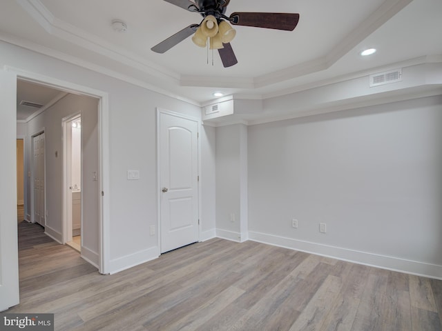 unfurnished bedroom featuring a raised ceiling, crown molding, light hardwood / wood-style flooring, and ceiling fan