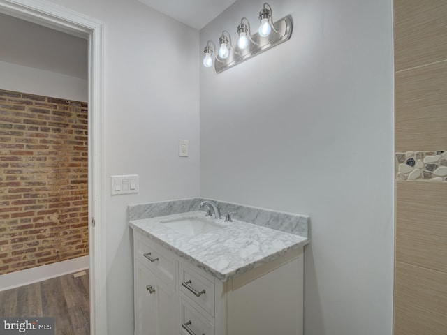 bathroom with vanity, brick wall, and hardwood / wood-style flooring