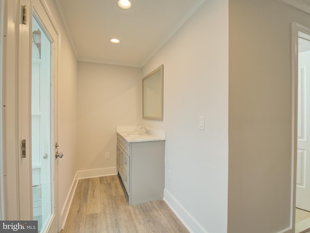 hallway with light hardwood / wood-style floors, ornamental molding, and sink