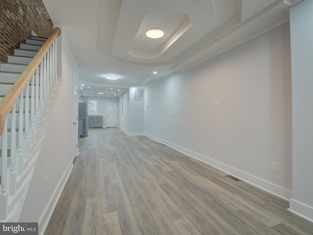 unfurnished living room with hardwood / wood-style flooring, a raised ceiling, and crown molding