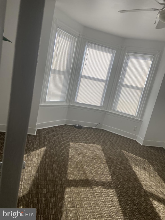 interior space featuring ceiling fan and dark carpet