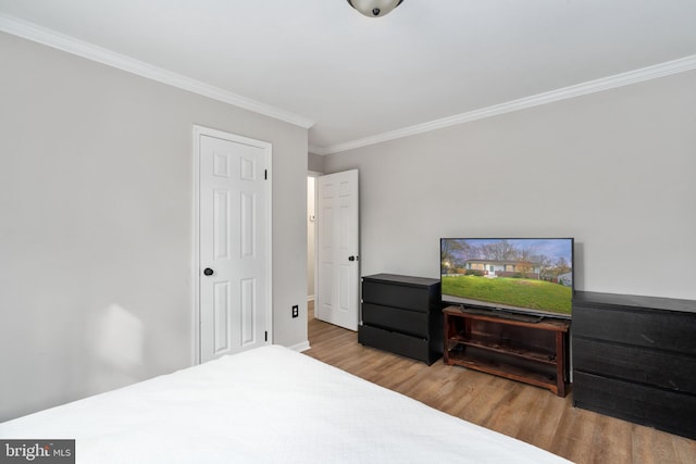 bedroom featuring ornamental molding and light wood-type flooring