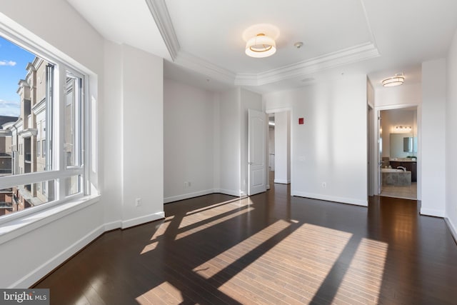 empty room with dark hardwood / wood-style floors, ornamental molding, and a tray ceiling