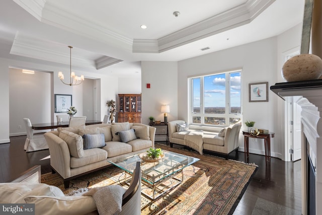 living room with dark hardwood / wood-style floors, a raised ceiling, crown molding, and a chandelier